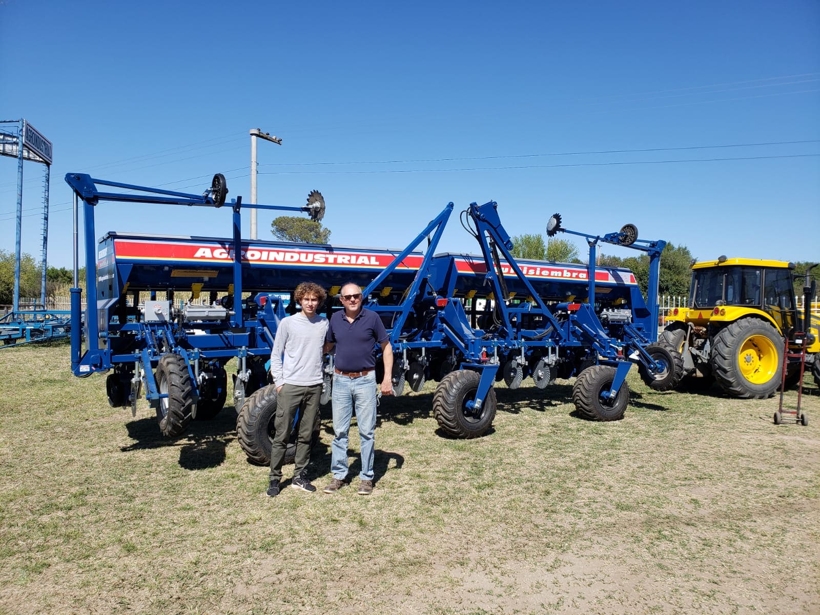 dos personas paradas junto a un equipo de multisiembra de agroindustrial